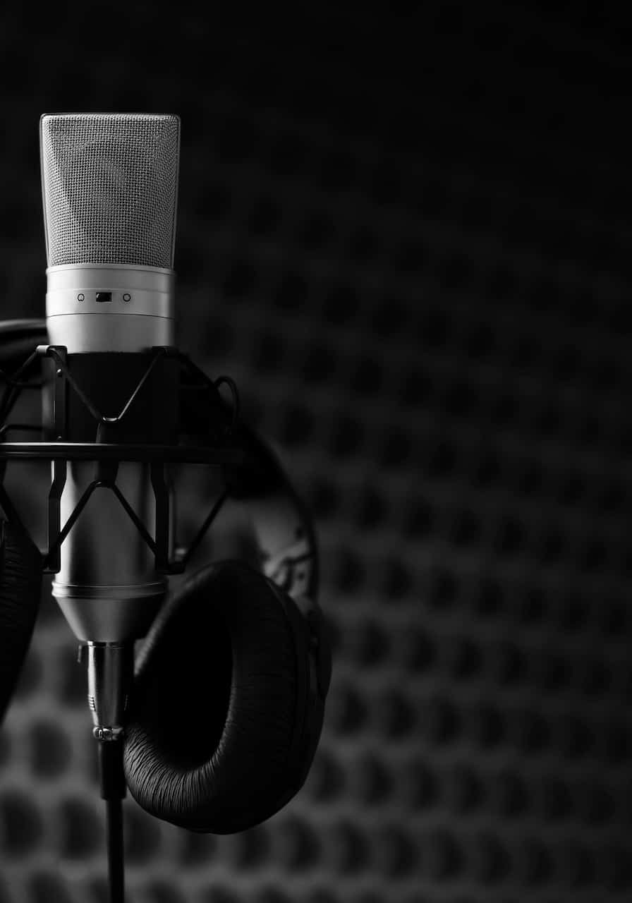 Studio microphone and headphones on mic stand against gray background